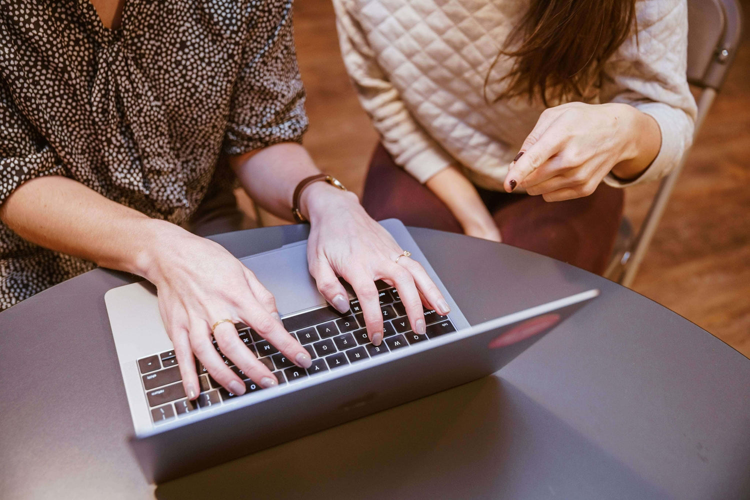 Two people using a laptop together at a table.