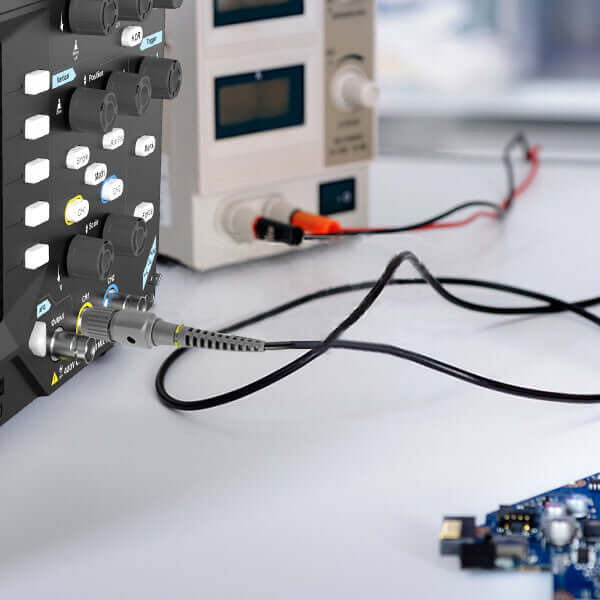 Digital oscilloscope measuring electronic circuit board signals on a workbench