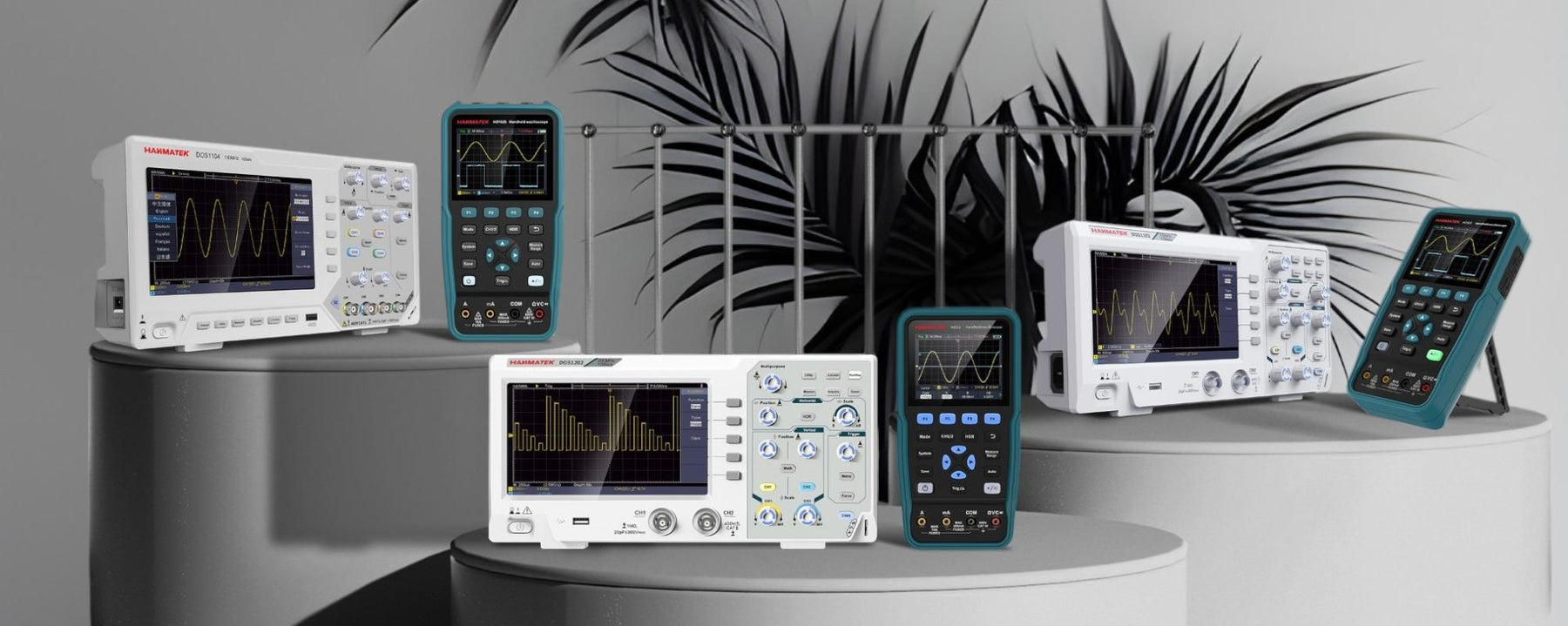 Digital benchtop and handheld oscilloscopes with waveform displays on a gray pedestal