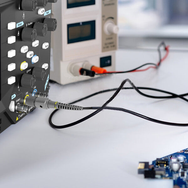 Hand using a probe on a circuit board while analyzing signals on a digital oscilloscope.
