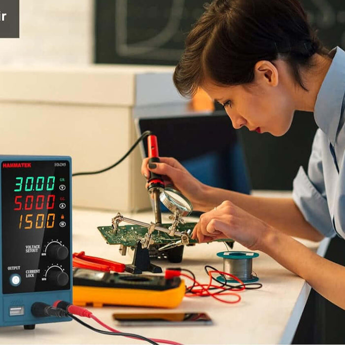 Woman using soldering iron and digital DC power supply for circuit board repair