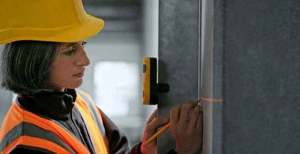 Professional using surveying and mapping tools for accurate measurements with a laser level and pencil