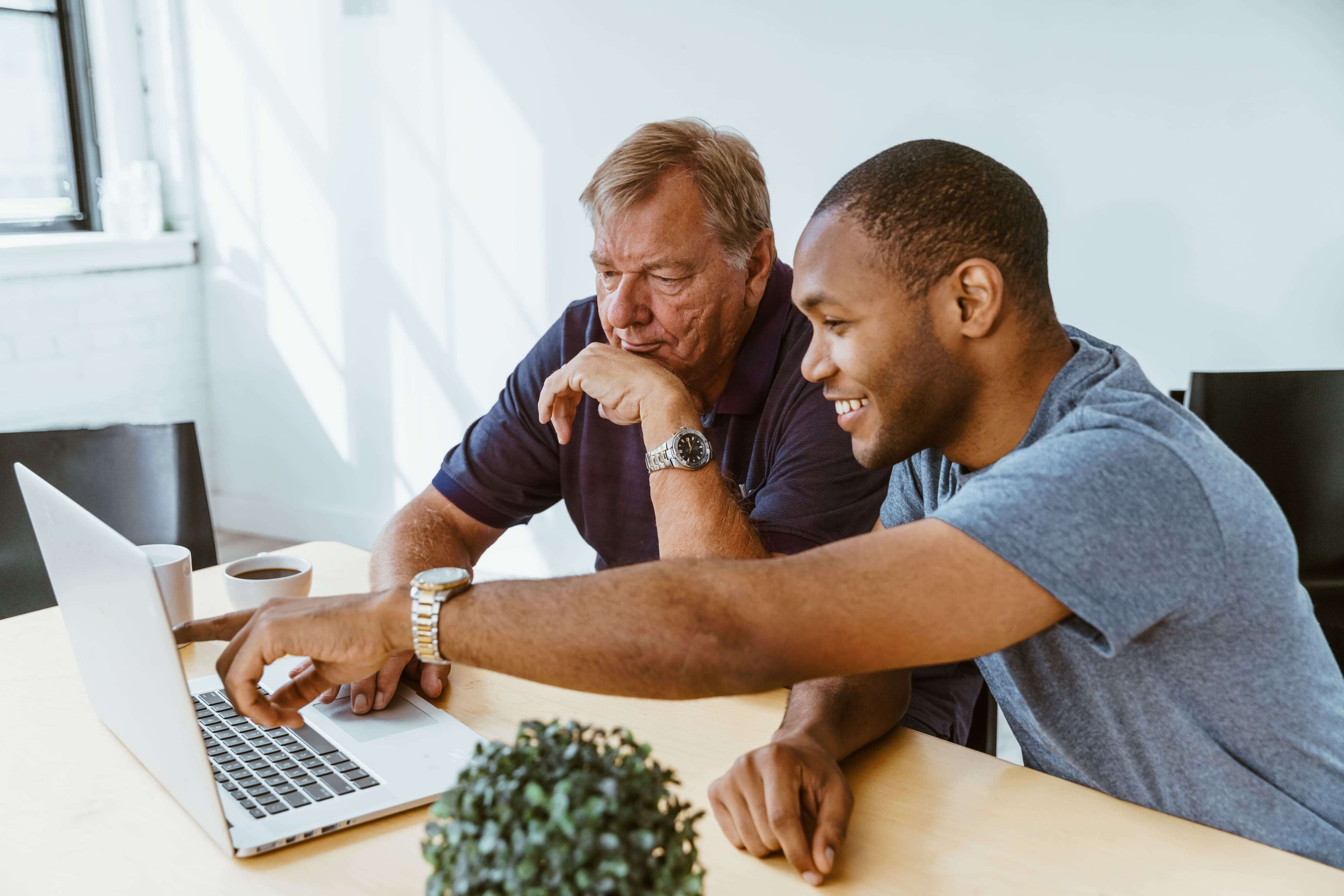 Two men looking at a laptop together in an office setting