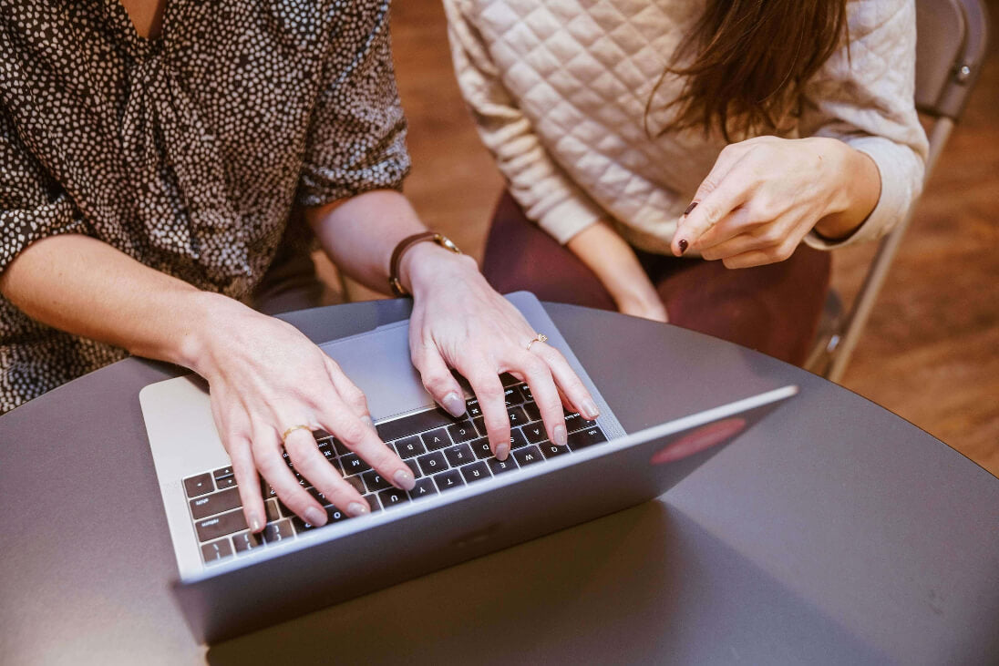 Two people using a laptop together at a table.